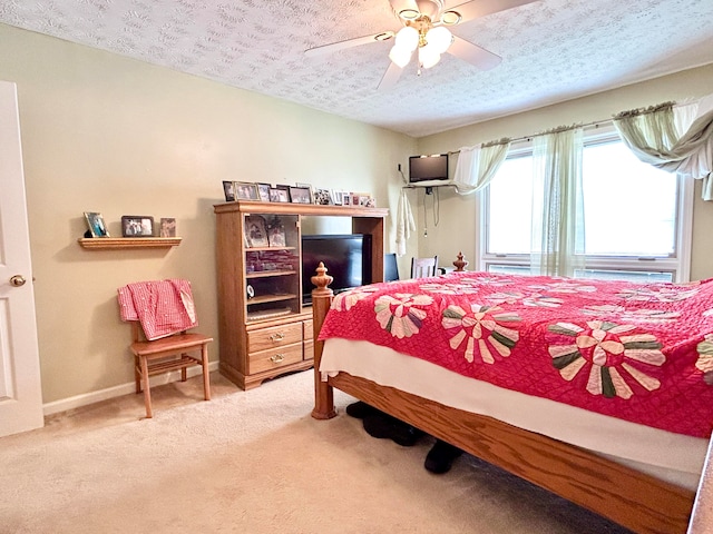 bedroom featuring light colored carpet, ceiling fan, and a textured ceiling