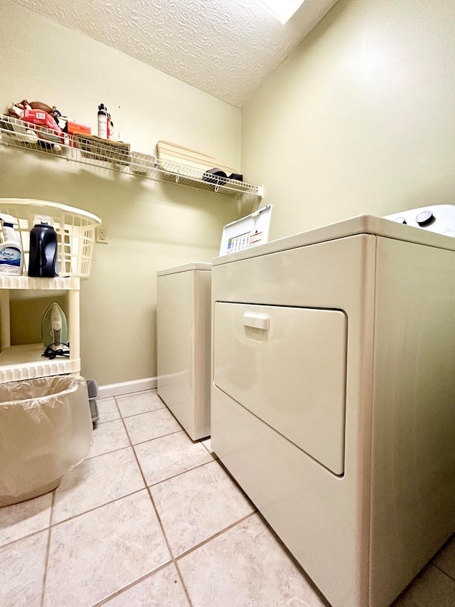 washroom with a textured ceiling, light tile flooring, and washing machine and clothes dryer