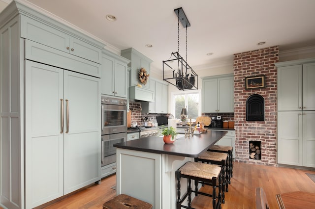 511 Boone Ave, Winchester, KY 40391 - kitchen with a kitchen island, stainless steel appliances, light hardwood / wood-style floors, pendant lighting, and ornamental molding