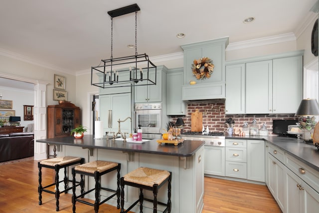511 Boone Ave, Winchester, KY 40391 - kitchen with a kitchen island with sink, a breakfast bar, decorative light fixtures, appliances with stainless steel finishes, and light hardwood / wood-style floors