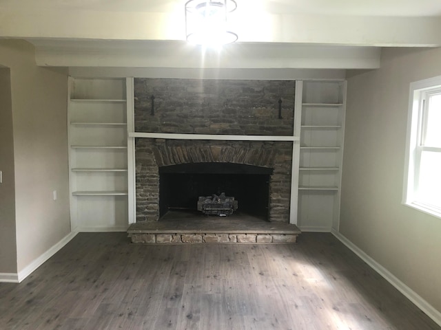 unfurnished living room with hardwood / wood-style flooring, a stone fireplace, a healthy amount of sunlight, and built in features