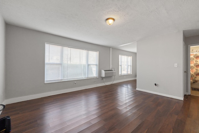 spare room with a textured ceiling, a wall mounted AC, and dark wood-type flooring