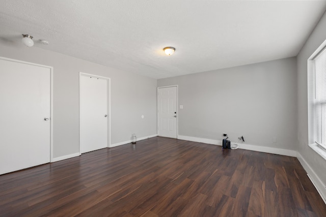 empty room with a textured ceiling and dark hardwood / wood-style floors