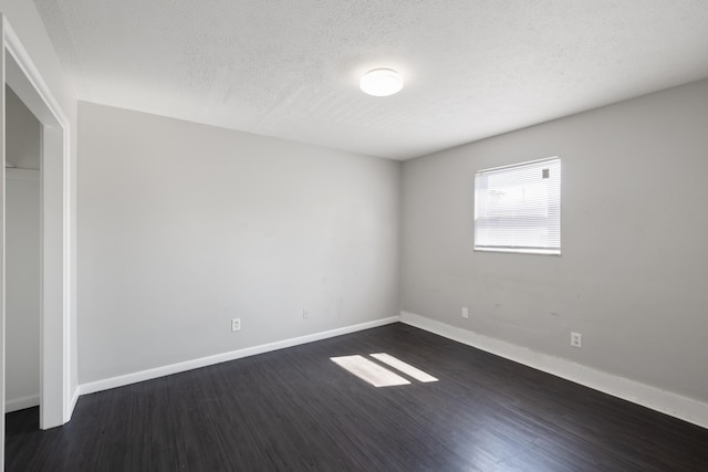 empty room featuring dark wood-type flooring and a textured ceiling