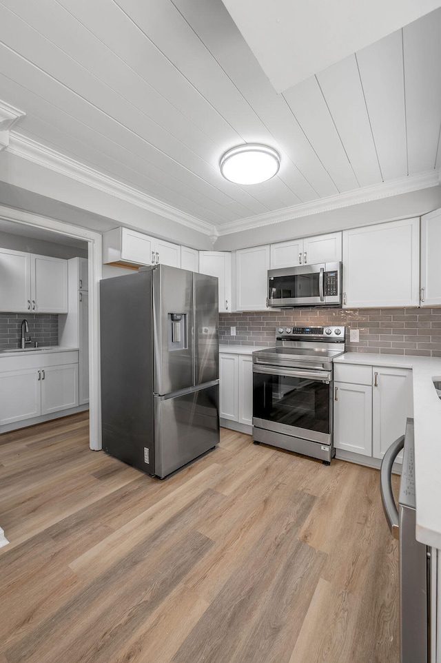 kitchen with ornamental molding, appliances with stainless steel finishes, backsplash, and light wood-type flooring