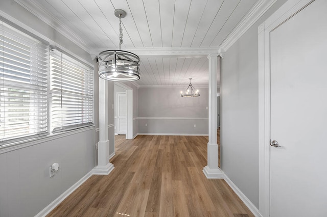 hall with decorative columns, crown molding, hardwood / wood-style flooring, and an inviting chandelier