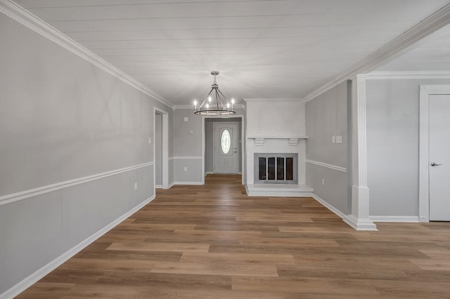 unfurnished living room with ornamental molding, a notable chandelier, hardwood / wood-style floors, and a fireplace