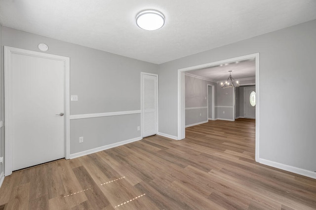 unfurnished room with an inviting chandelier and wood-type flooring