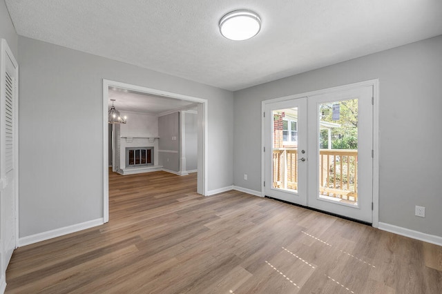 doorway featuring a textured ceiling, hardwood / wood-style floors, a notable chandelier, and french doors