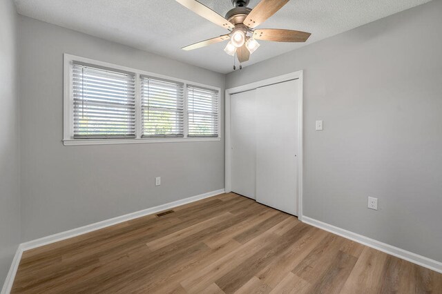 unfurnished bedroom featuring hardwood / wood-style floors, a closet, and ceiling fan