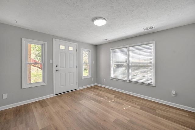 foyer with light hardwood / wood-style flooring and a textured ceiling