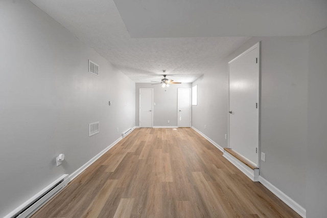 spare room with a textured ceiling, ceiling fan, light wood-type flooring, and baseboard heating