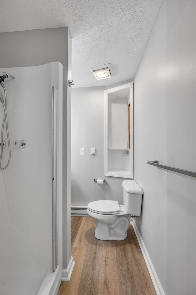 bathroom with a baseboard heating unit, a textured ceiling, hardwood / wood-style floors, toilet, and a shower