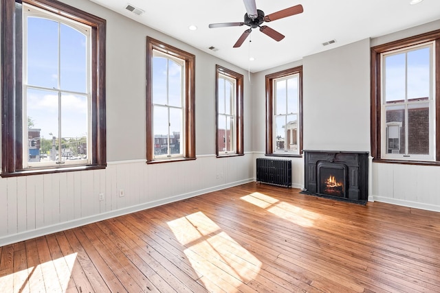 unfurnished living room with hardwood / wood-style floors, ceiling fan, and radiator