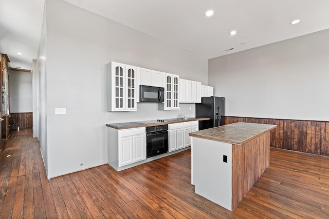 kitchen featuring a center island, white cabinetry, black appliances, and dark wood-type flooring