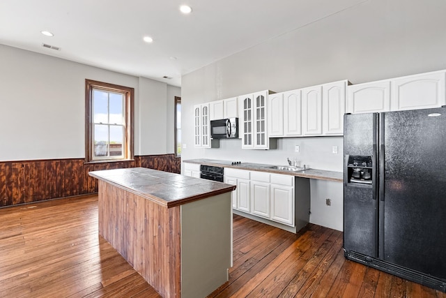 kitchen with a kitchen island, tile counters, black appliances, white cabinetry, and hardwood / wood-style floors