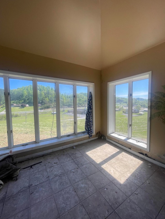 unfurnished room with high vaulted ceiling and tile flooring