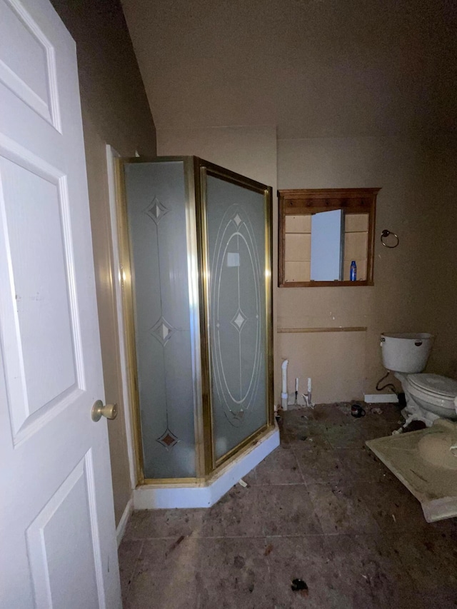 bathroom featuring a shower with shower door and toilet