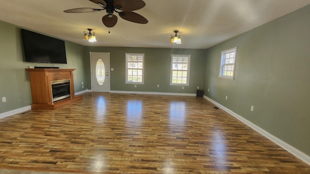 unfurnished living room with ceiling fan and dark wood-type flooring