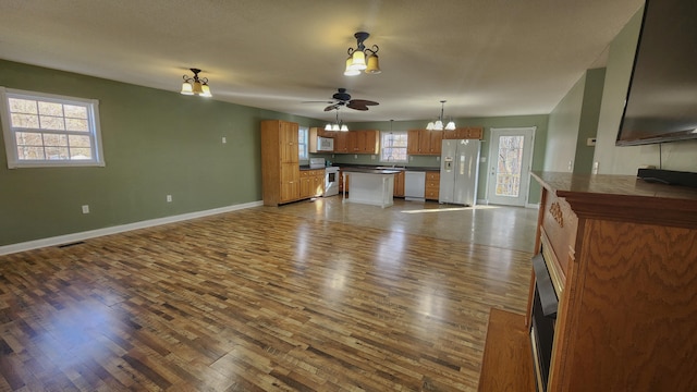 unfurnished living room with ceiling fan with notable chandelier, hardwood / wood-style floors, and sink