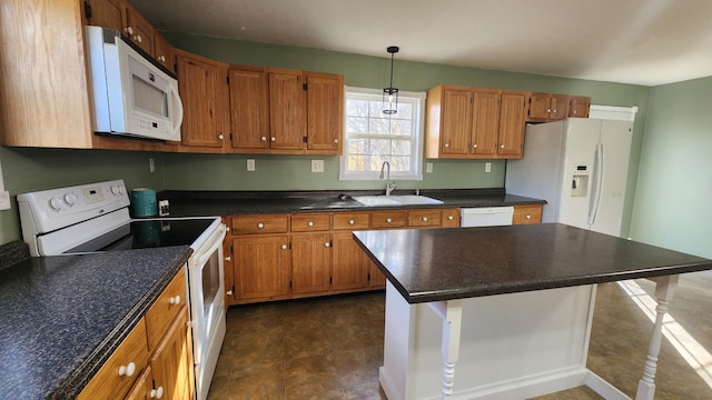 kitchen featuring a breakfast bar area, white appliances, dark tile flooring, sink, and pendant lighting