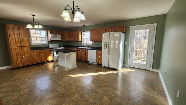 kitchen featuring decorative light fixtures, sink, white appliances, and a chandelier