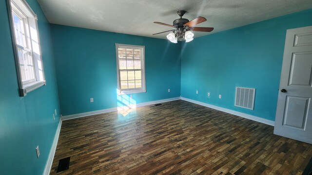 empty room with ceiling fan, dark hardwood / wood-style floors, and a textured ceiling