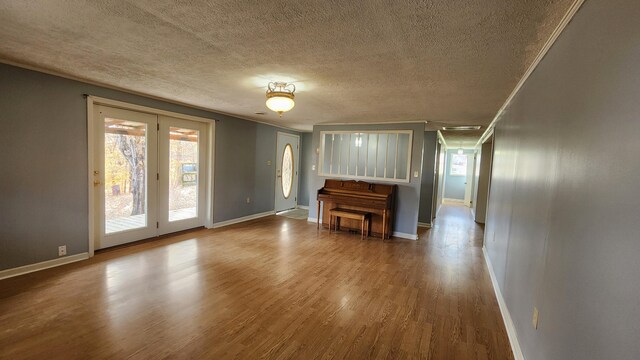 unfurnished living room featuring wood-type flooring, a textured ceiling, and ornamental molding