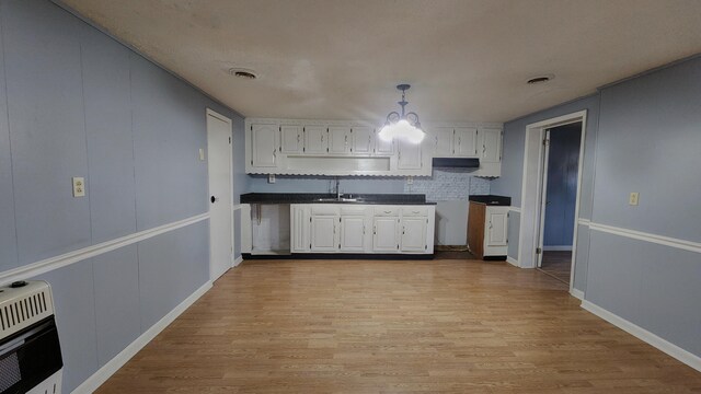 kitchen featuring decorative light fixtures, light hardwood / wood-style floors, tasteful backsplash, white cabinetry, and sink