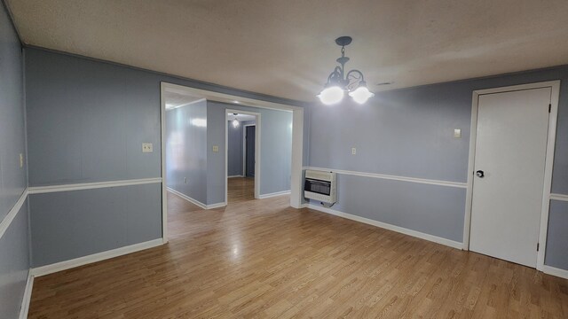 unfurnished room with a textured ceiling, light wood-type flooring, and an inviting chandelier