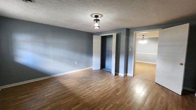 unfurnished bedroom with hardwood / wood-style flooring, a closet, and a textured ceiling