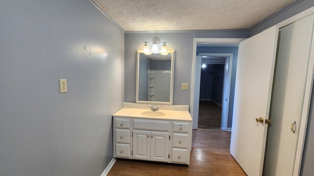 bathroom with ornamental molding, vanity, hardwood / wood-style flooring, and a textured ceiling