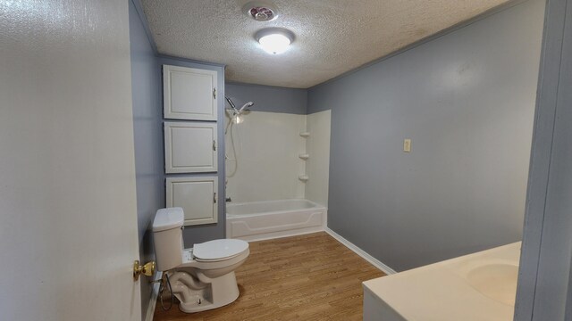 full bathroom featuring shower / bathing tub combination, vanity, hardwood / wood-style floors, toilet, and a textured ceiling