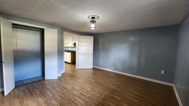 unfurnished bedroom featuring a closet, a textured ceiling, and hardwood / wood-style flooring