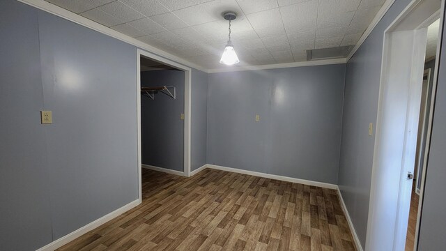 empty room with wood-type flooring and crown molding