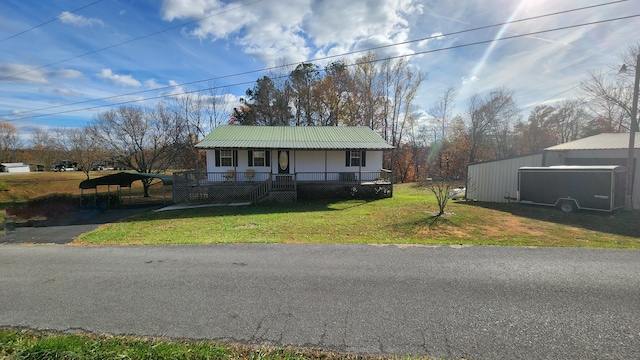 view of front of property featuring a front yard, a garage, an outdoor structure, and covered porch