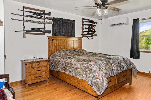 bedroom featuring a wall mounted AC, light hardwood / wood-style flooring, and ceiling fan