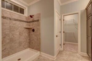 bathroom featuring tiled shower, tile patterned floors, and crown molding