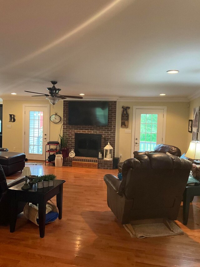 living room featuring ceiling fan, ornamental molding, a fireplace, and hardwood / wood-style floors