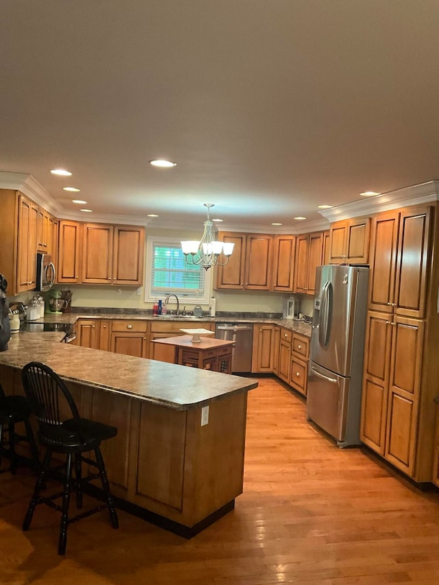 kitchen featuring light hardwood / wood-style flooring, appliances with stainless steel finishes, kitchen peninsula, hanging light fixtures, and a breakfast bar