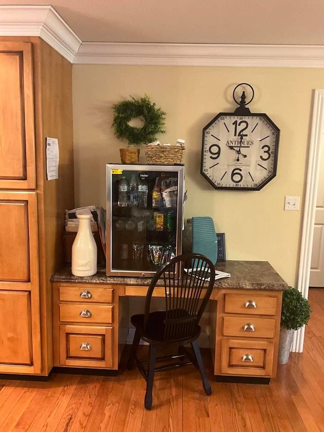 office area featuring crown molding, built in desk, and light wood-type flooring