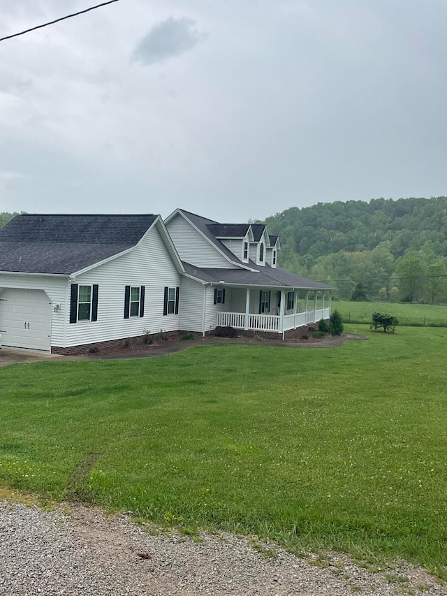 view of front of home with a front yard, covered porch, and a garage