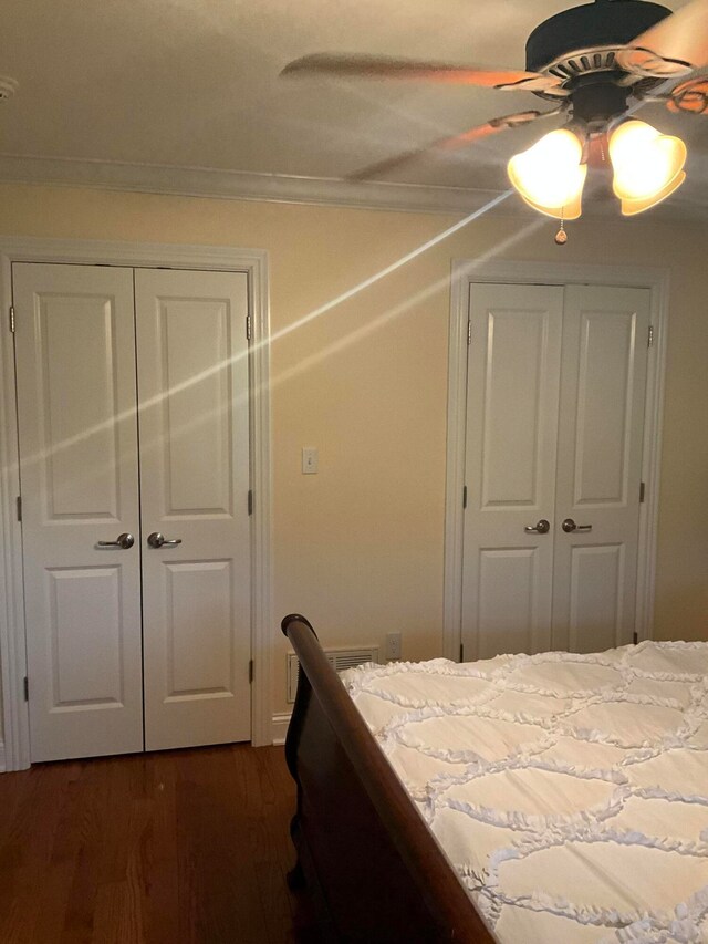 unfurnished bedroom featuring dark hardwood / wood-style floors, two closets, and ceiling fan