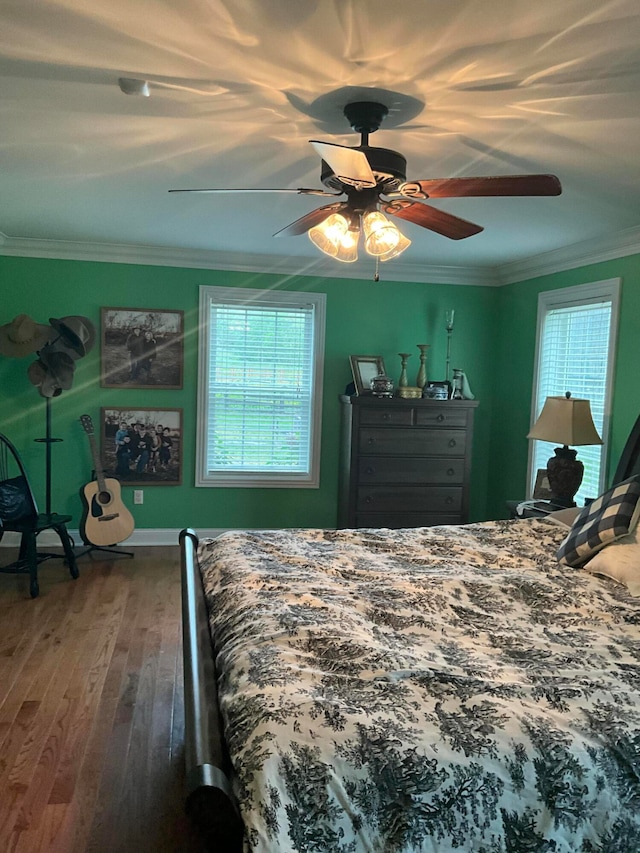 bedroom with ceiling fan, crown molding, wood-type flooring, and multiple windows