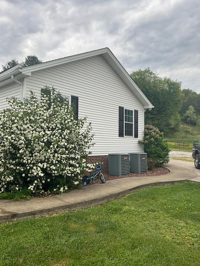 view of property exterior with cooling unit and a yard