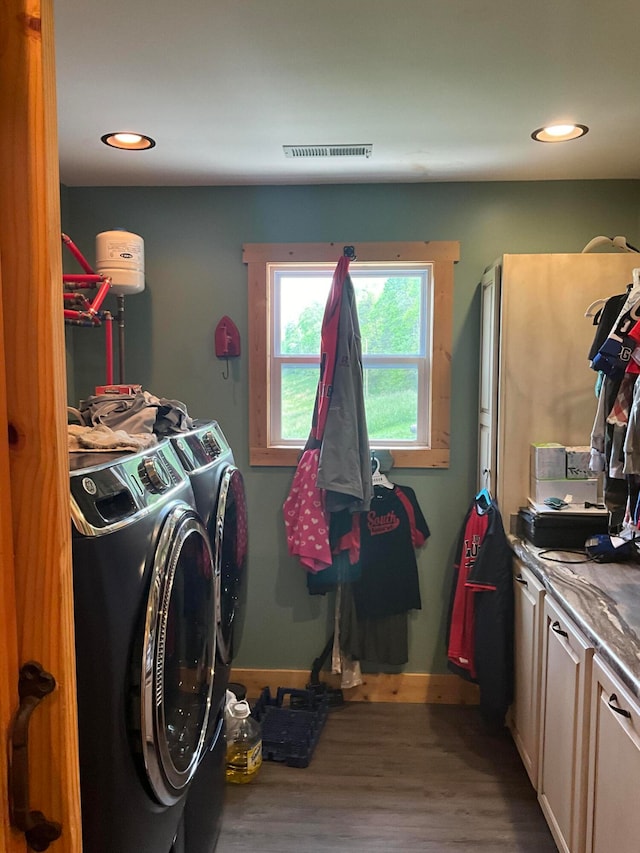 laundry room featuring cabinets, washing machine and dryer, and hardwood / wood-style flooring