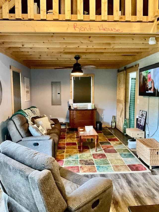 living room with beamed ceiling, a barn door, electric panel, and hardwood / wood-style floors