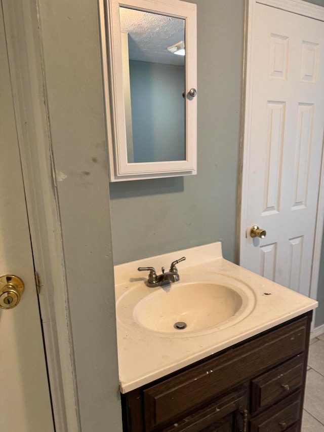 bathroom with vanity, a textured ceiling, and tile patterned flooring