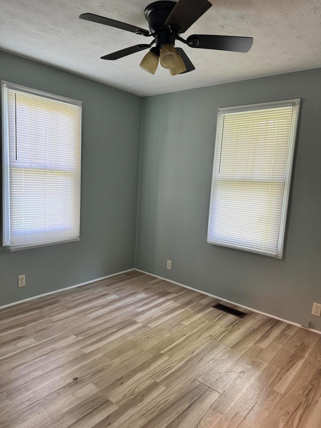 empty room featuring ceiling fan, a textured ceiling, and light hardwood / wood-style flooring