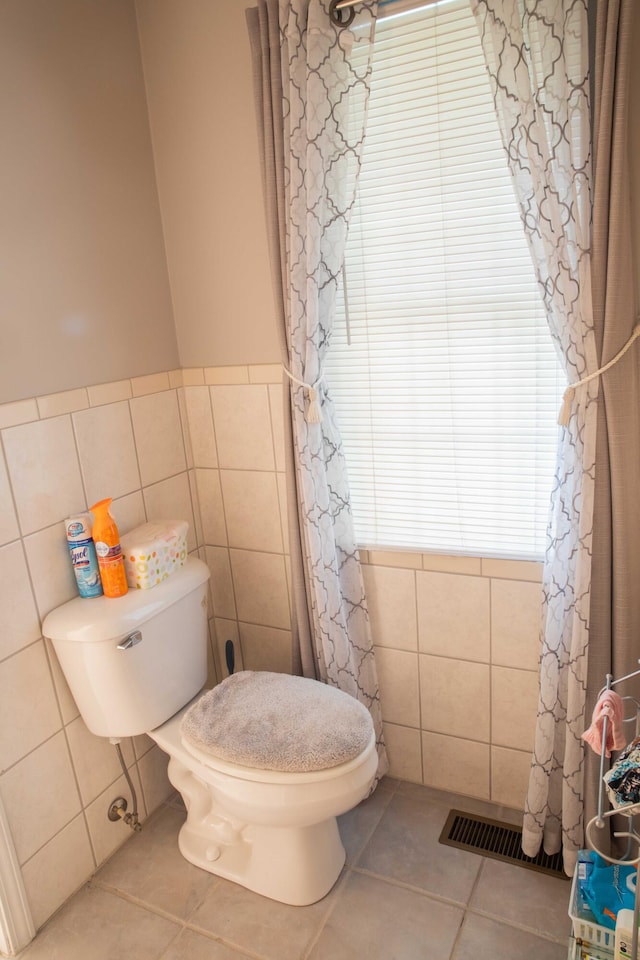 bathroom with tile walls, tile floors, and toilet